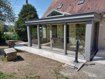 Réalisation d'une maçonnerie de véranda avec une grande ouverture entre les deux pièces de 4 mètres de long une terrasse sur plot